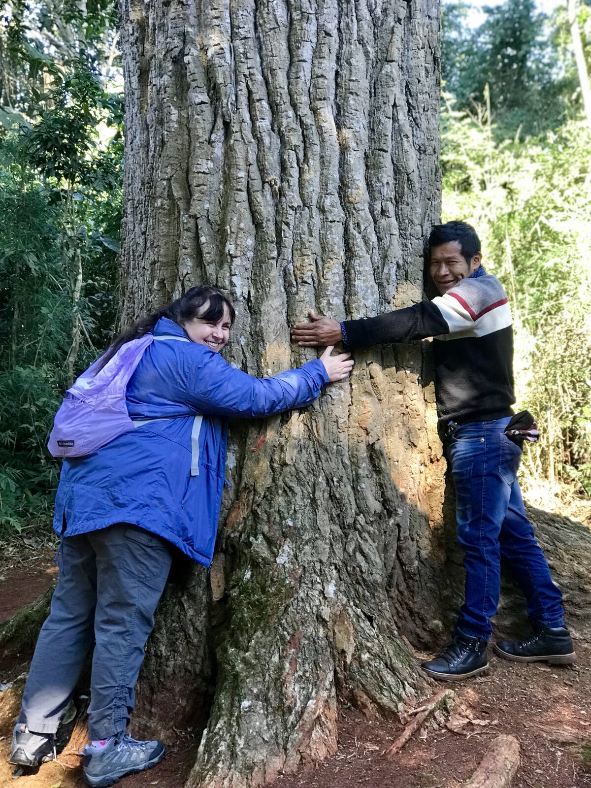 Abrazando un árbol nativo junto a un referente de la comunidad